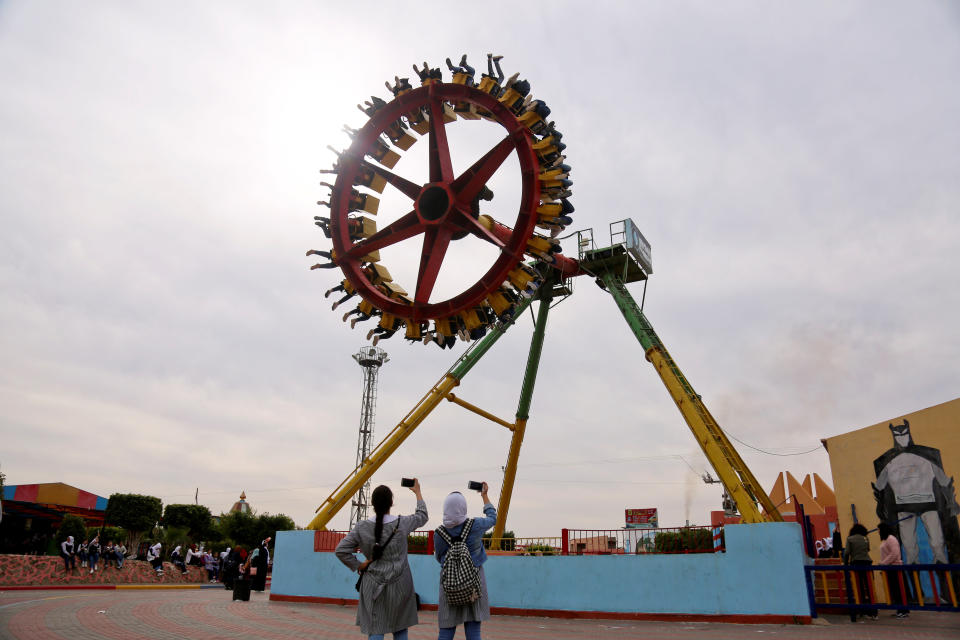 Palestinian schoolgirls take pictures of people enjoying a ride at an amusement park in Gaza City, Nov. 29, 2018. (Photo: Samar Abo Elouf/Reuters)