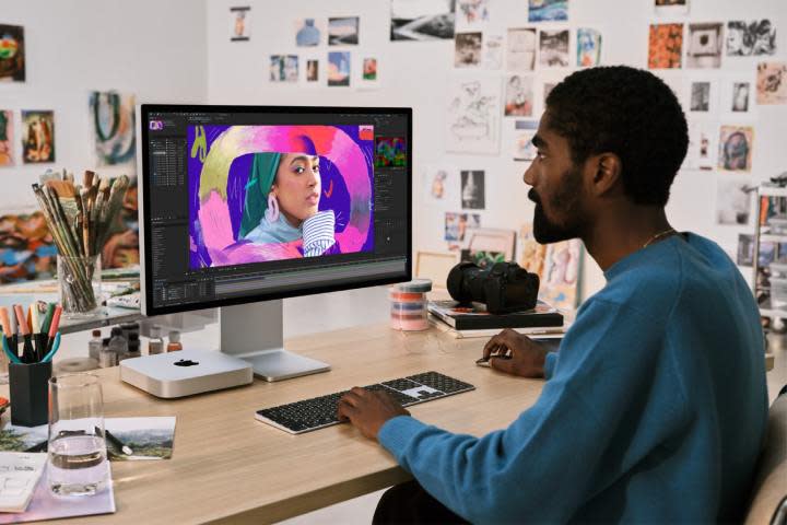 Someone using a Mac Mini while sitting at a desk.