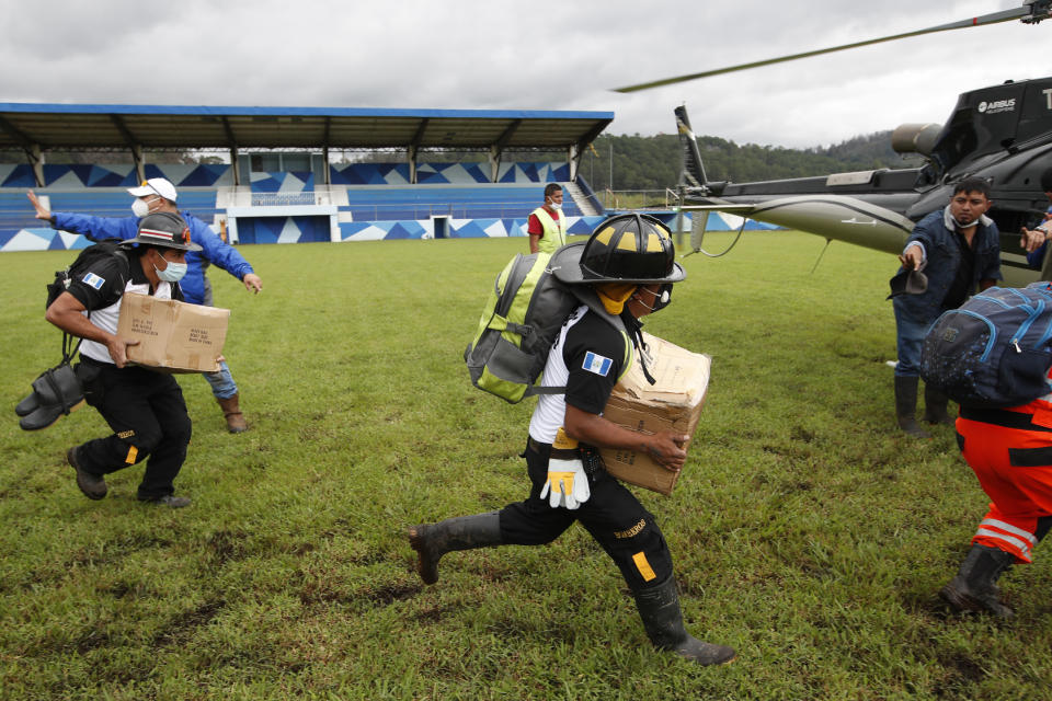 ARCHIVO - En esta foto de archivo del 7 de noviembre de 2020, los bomberos voluntarios se apresuran a un helicóptero que espera para cargar ayuda de emergencia para ser transportada a una zona cercana donde se cree que los residentes están enterrados por un deslizamiento de tierra masivo provocado por la lluvia, durante los esfuerzos de búsqueda y rescate en San Cristóbal Verapaz, luego de la tormenta tropical Eta. La búsqueda finalmente se suspendió después de recuperar algunos cuerpos y declarar a unas 100 personas desaparecidas. (AP Foto/Moisés Castillo, Archivo)