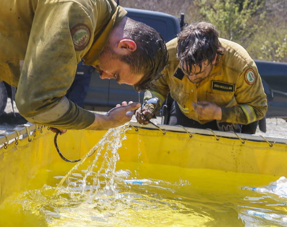 Department of Natural Resources and Renewables crew members Matt Sartoris (left) and Ryan McLellan cool off while fighting wildfires near Tantallon, Nova Scotia, Thursday, June 1, 2023. Rain and a rainy forecast for the weekend have fire officials hopeful they can get the largest wildfire ever recorded in Canada’s Atlantic Coast province of Nova Scotia under control. (Communications Nova Scotia /The Canadian Press via AP)