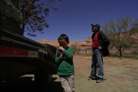 In this April 27, 2020, photo, Charlie Whitehouse, right, waits with a load of hay as a boy holds a kitten named Popcorn Ball in Oljato-Monument Valley, Utah, on the Navajo reservation. Even before the pandemic, people living in rural communities and on reservations were among the toughest groups to count in the 2020 census. (AP Photo/Carolyn Kaster)