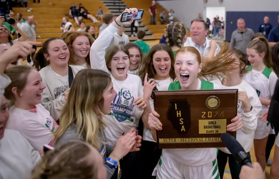 Peoria Notre Dame's Brigid Dooley holds the Class 2A super-sectional plaque as she celebrates with her teammates and fans after their 55-39 victory over Rock Island-Alleman for a berth in the state finals Monday, Feb. 26, 2024 at Bureau Valley High School in Manlius.