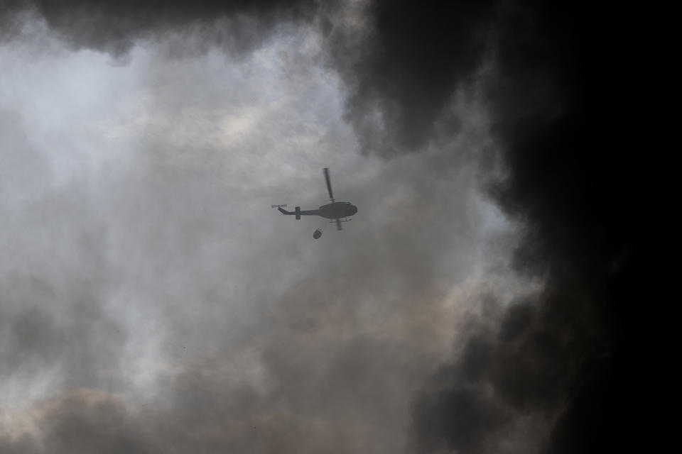 An army helicopter drops water on a fire at warehouses at the seaport in Beirut, Lebanon, Thursday, Sept. 10. 2020. A huge fire has broken out at the Port of Beirut, sending up a thick column of black smoke and raising new panic among traumatized residents after last month’s catastrophic blast at the same site killed nearly 200 people. (AP Photo/Hassan Ammar)