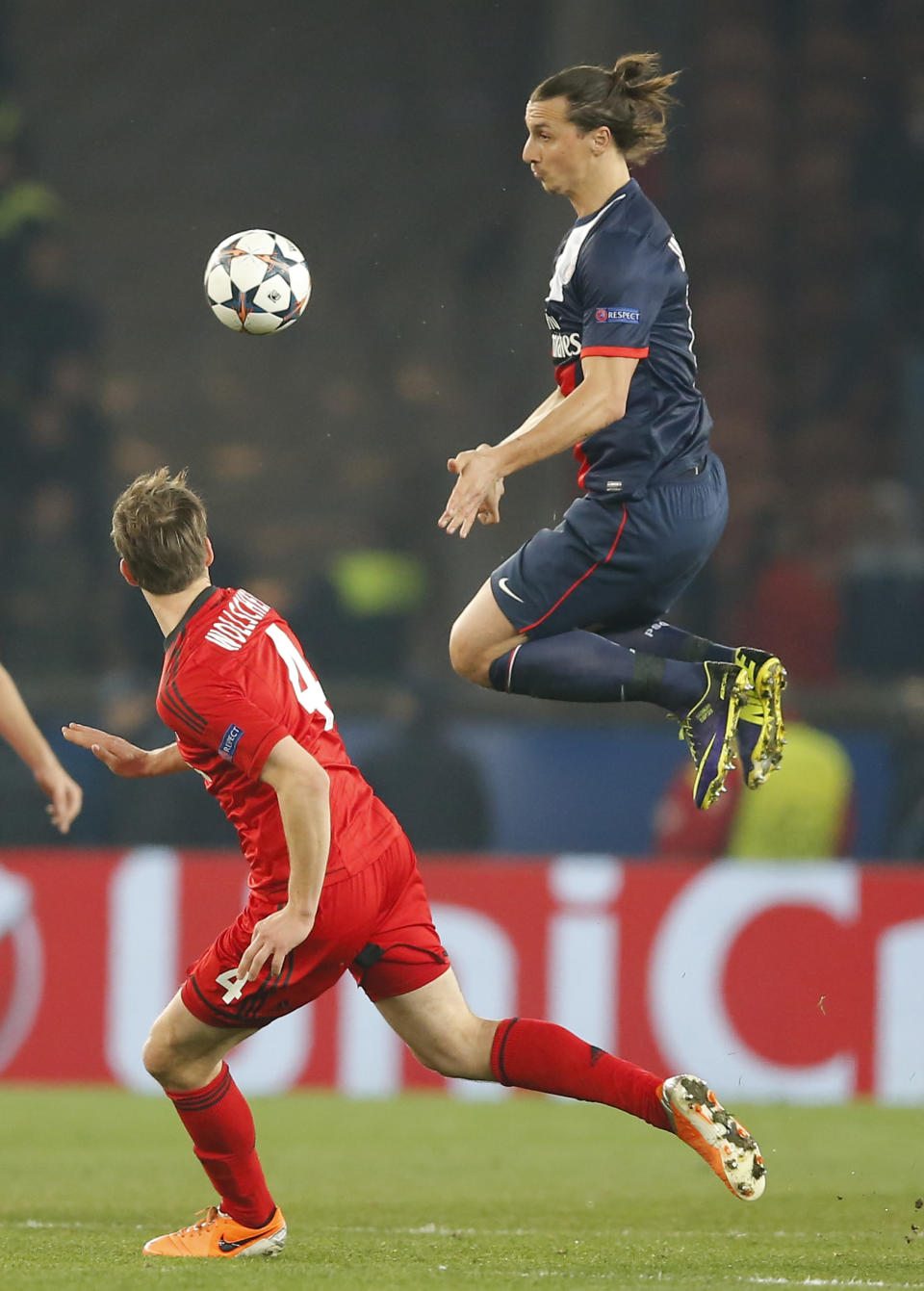 PSG's Zlatan Ibrahimovic, right, jumps in the air for a high ball while Leverkusen's Philipp Wollscheid, center, looks on during a Champions League last 16 second leg soccer match between Paris Saint Germain and Bayer Leverkusen at Parc des Princes stadium in Paris, Wednesday, March 12, 2014. (AP Photo/Michel Euler)