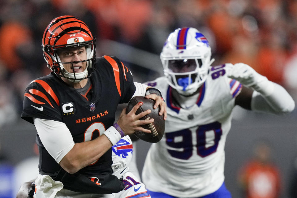 Cincinnati Bengals quarterback Joe Burrow, left, holds the football with his hands, including a bloody finger, while being chased by Buffalo Bills defensive end Shaq Lawson during the first half of an NFL football game, Sunday, Nov. 5, 2023, in Cincinnati. (AP Photo/Carolyn Kaster)