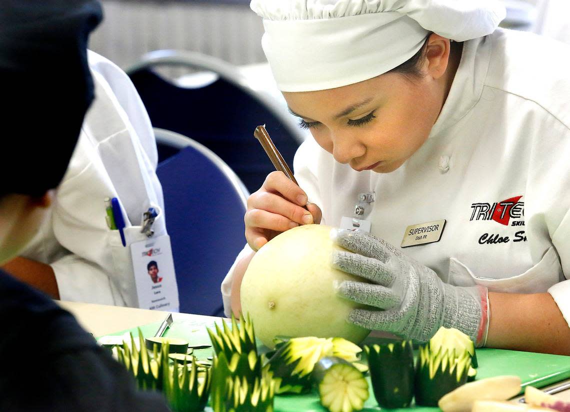 A culinary arts student at Tri-Tech Skills Center concentrates on carving flower in a melon during a 2019 presentation.