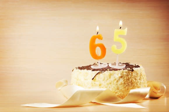 Cake with number candles on top spelling out 65.