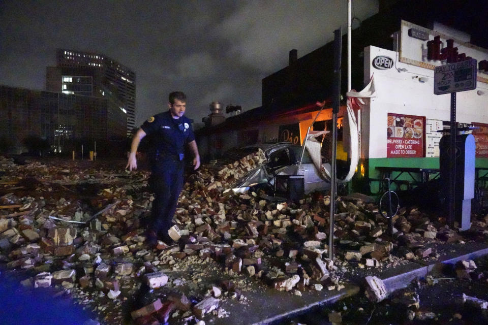 Police Detective Alexander Reiter walk through debris from a collapsed building.