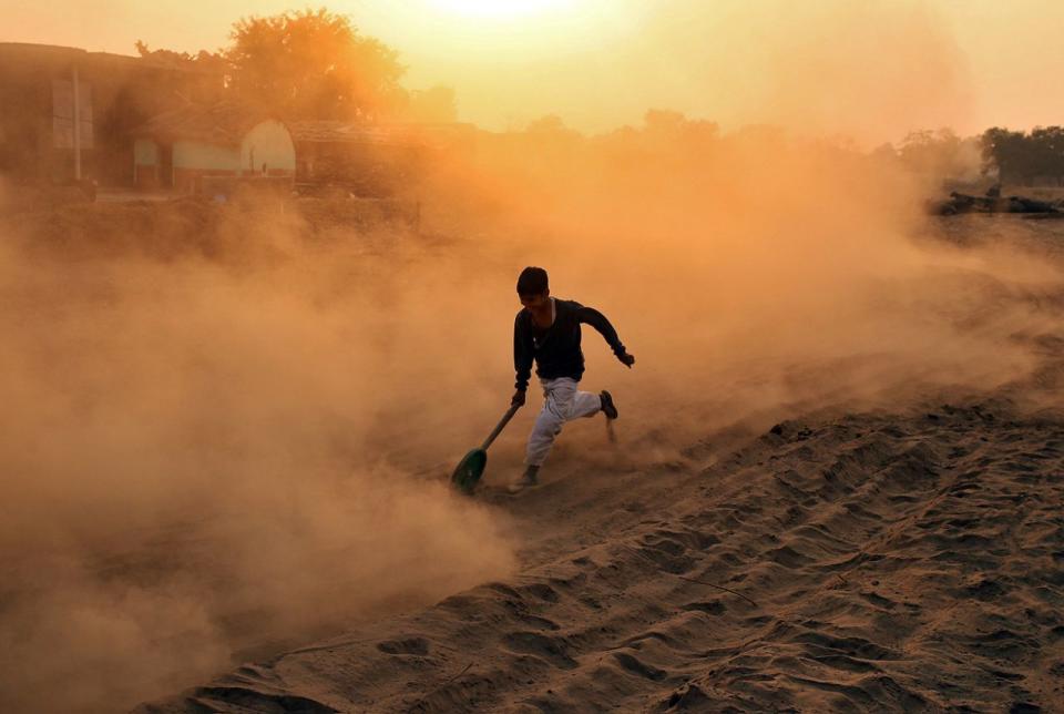 <p>Ein Junge spielt in Jammu in Indien auf einer staubigen Straße mit einem selbstgebastelten Rad. (Bild: Mukesh Gupta/ Reuters) </p>