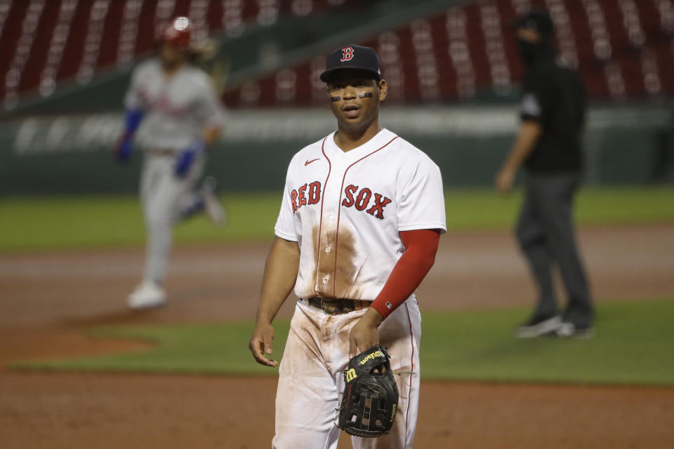 Boston Red Sox third baseman Rafael Devers walks away as Philadelphia Phillies' Bryce Harper, left, rounds the bases after his three run home run during the sixth inning of a baseball game Tuesday, Aug. 18, 2020, at Fenway Park in Boston. (AP Photo/Winslow Townson)