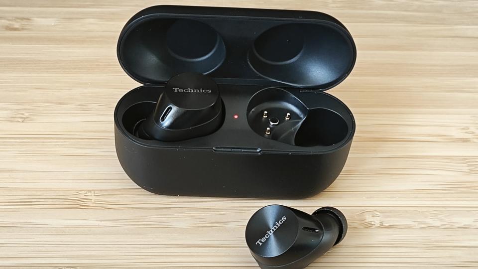 A pair of wireless Panasonic Technics EAH-AZ60M2 earbuds and a charging case on a wooden desk