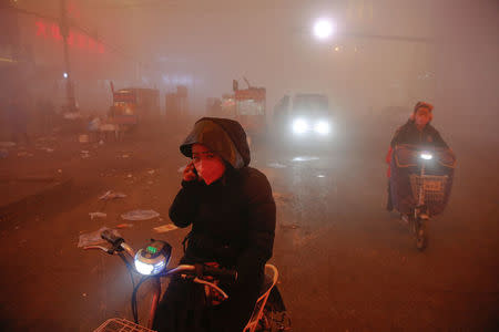 People make their way through heavy smog on an extremely polluted day with red alert issued, in Shengfang, Hebei province, China. REUTERS/Damir Sagolj