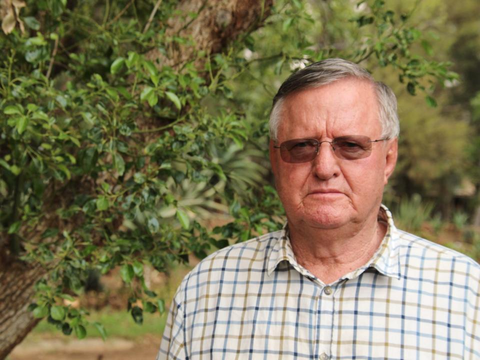 John Hume, owner of private rhino breeding in South Africa, standing in front of a tree.