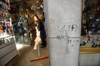 A woman clears a shop from water in Venice, Italy, Saturday, Nov. 16, 2019. High tidal waters returned to Venice on Saturday, four days after the city experienced its worst flooding in 50 years, marked by the writing on the wall. (AP Photo/Luca Bruno)