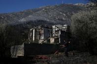 A firefighter arranges a hose outside a burned down house during a wildfire on Mount Hymettus, near Athens