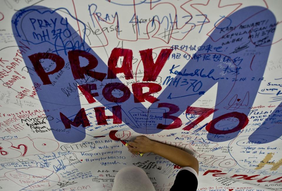Un trabajador de Malaysia Airlines escribe un mensaje esperanzador para los pasajeros del vuelo de la compañía desaparecido, en Kula Lumpur, el viernes 14 de marzo de 2014 ( | Manan Vatsyayana)