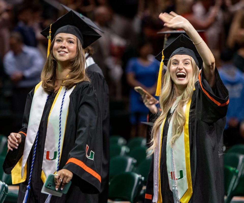 Gillian Drexler, right, greets her family in the stands as Charleigh Peters, left, leads the way down the aisle as they enter the Watsco Cente for UM’s spring commencement ceremonies on Friday, May 12, 2023 in Coral Gables, Florida. Jose A. Iglesias/jiglesias@elnuevoherald.com