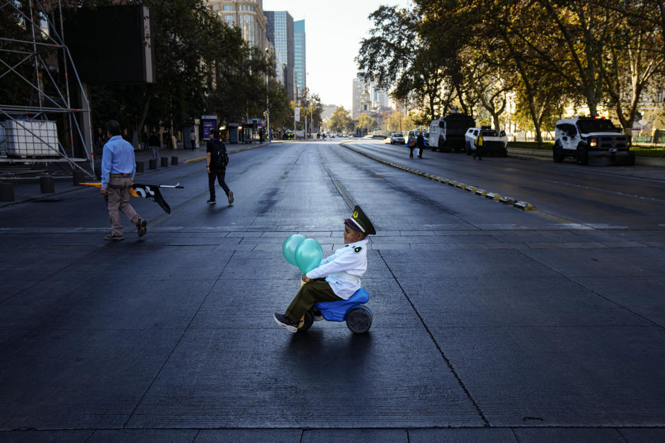 A child dressed as a police officer and accompanied by his parents, rides his toy vehicle to a demonstration seeking justice for police officers killed in the line of duty, in Santiago, Chile, Saturday, April 27, 2024. Three police officers were killed early Saturday, in Cañete, Chile's Bío Bío region. (AP Photo/Esteban Felix)