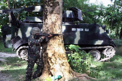 A Philippine soldier takes his position next to a tank in the town of Talayan, on the southern island of Mindnano on August 6, 2012, after members of a breakaway Muslim rebel group launched simultaneous attacks across 11 towns in the southern Philippines. Philippine troops have found four bodies including the mutilated corpses of two soldiers