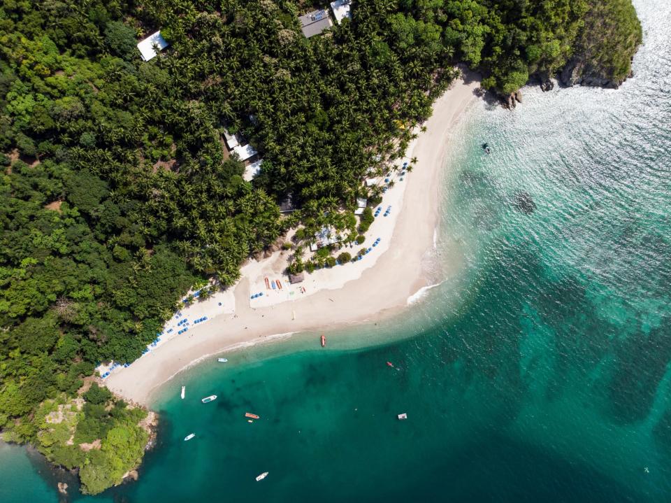 Learn more about the best times to visit Costa Rica. 
Pictured: an aerial view of a Costa Rica beach with lush greenery 