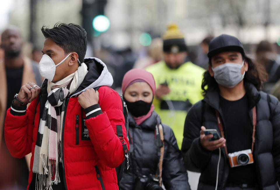 People wearing face masks walk along Oxford Street in London, Saturday, March 14, 2020. For most people, the new COVID-19 coronavirus causes only mild or moderate symptoms, such as fever and cough. For some, especially older adults and people with existing health problems, it can cause more severe illness, including pneumonia.(AP Photo/Frank Augstein)