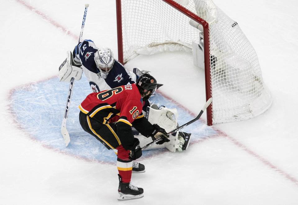 Winnipeg Jets goalie Connor Hellebuyck (37) is scored on by Calgary Flames' Tobias Rieder (16) during the second period of an NHL hockey playoff game Saturday, Aug. 1, 2020 in Edmonton, Alberta. (Jason Franson/The Canadian Press via AP)