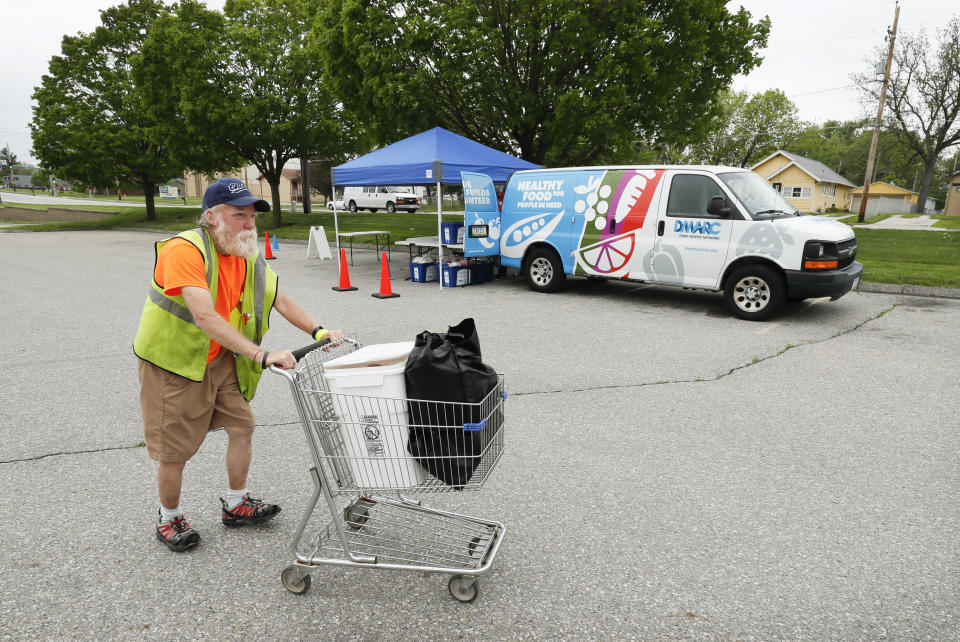 Lewis Claussen pushes his cart after picking up food at a Des Moines Area Religious Council Food Pantry stop, Wednesday, May 20, 2020, in Des Moines, Iowa. As food banks have struggled to meet soaring demand from people suddenly out of work because of the coronavirus outbreak, it has been especially troubling to see farmers have to bury produce, dump milk and euthanize hogs. Now some states are spending more money to help pay for food that might otherwise go to waste, the U.S. Agriculture Department is spending $3 billion to help get farm products to food banks, and a senator is seeking $8 billion more to buy farm produce for food banks. (AP Photo/Charlie Neibergall)