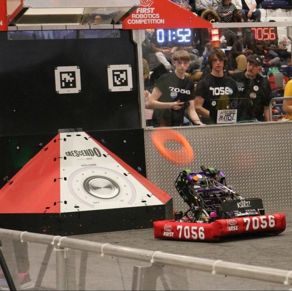 The drive team is hyper focused as their robot, Kurt, shoots a “note” to score points for their alliance.