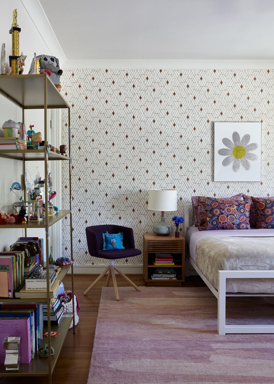 In this bedroom, decorated for the couple’s preteen daughter, a patterned wallpaper from Hygge & West with copper hues is softened by a pale pink rug from Joseph Carini Carpets. The white iron bed is from Room & Board.