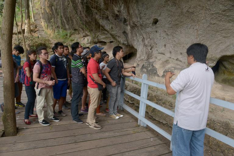 In this photo taken February 16, 2014, Filipino students look at the carvings on a rock wall in Binangonan east of Manila