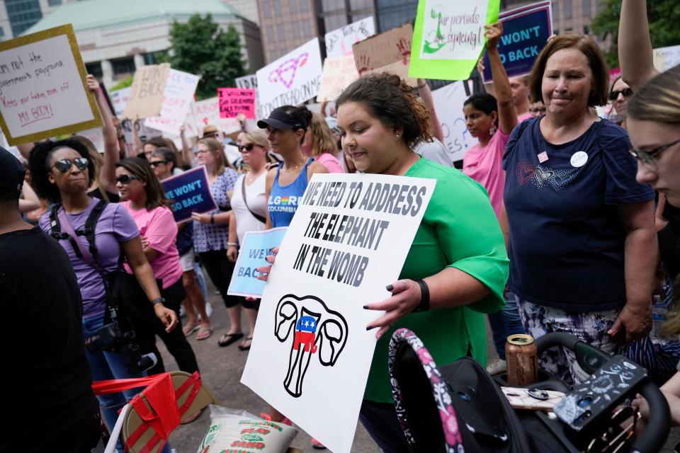 Amber Stanley, of Baltimore in Fairfield County, holds a sign Sunday during a rally organized by the Democratic Party at the Ohio Statehouse.