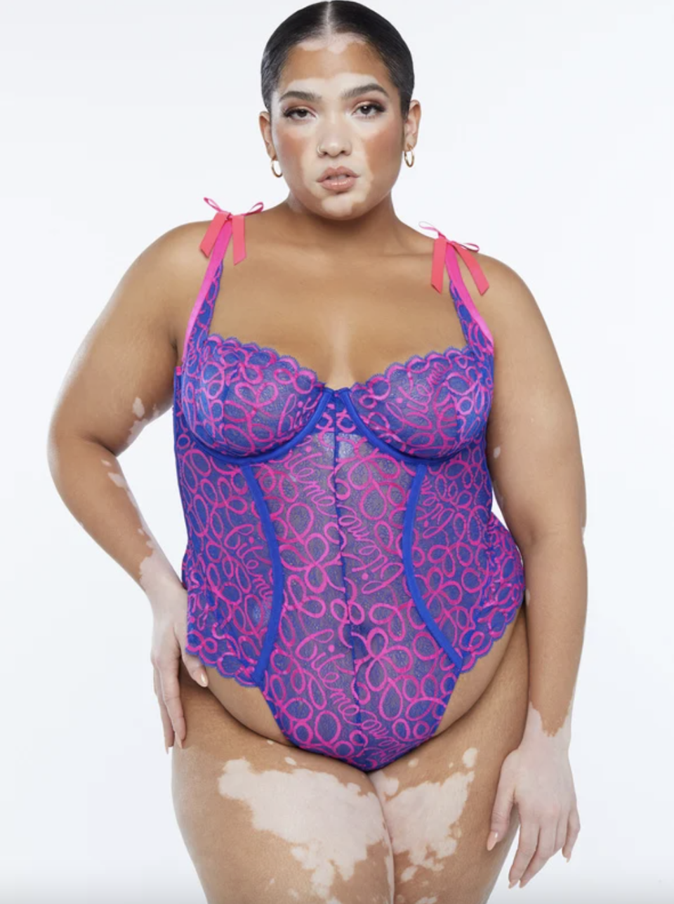 plus size model in Ribbon Writing Lace Teddy in purple and pink lace (Photo via Savage x Fenty)