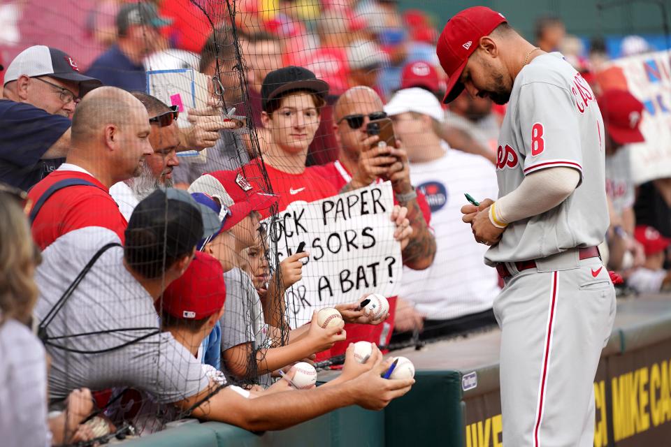Philadelphia Phillies right fielder Nick Castellanos (8) signs autographs for fans prior to the first inning of a baseball game against the Philadelphia Phillies, Monday, Aug. 15, 2022, at Great American Ball Park in Cincinnati. 