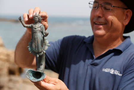 An Israel Antiquities Authority (IAA) employee holds a part of a statue, which the IAA estimates to be around 1600 years old, after it was recovered from a merchant ship in the ancient harbor of the Caesarea National Park May 16, 2016. REUTERS/ Baz Ratner