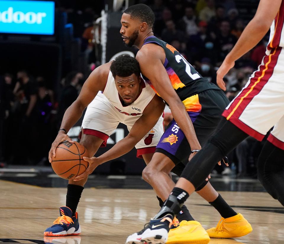 Phoenix Suns' Mikal Bridges, center right, plays tight defense on Miami Heat's Kyle Lowry, left, during the first half of an NBA basketball game Saturday, Jan. 8, 2022, in Phoenix.