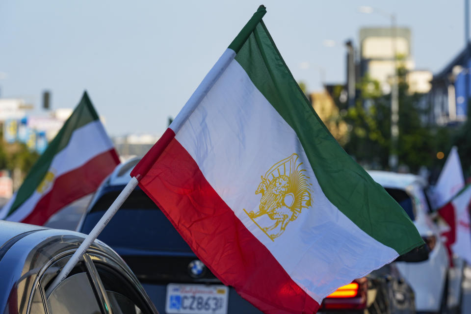 A caravan of vehicles rides while flying the Lion and Sun flag along Westwood Boulevard, in the so-called "Tehrangeles" neighborhood in the Westwood district of Los Angeles, Monday, May 20, 2024. The Lion and Sun flag was Iran's official flag for centuries until the 1979 revolution. The ancient Persian flag continues to be used by the Iranian diaspora, monarchists and opposition groups as a symbol of Iran's pre-Islamic heritage and resistance against the Islamic Republic. (AP Photo/Damian Dovarganes)