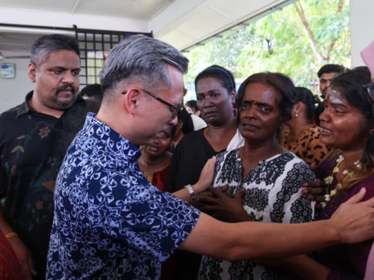 Malaysia’s communications minister Fahmi Fadzil, dressed in blue, speaks with Rajeswary Appahu’s mother, who is in white, at the social media influencer’s funeral in Gombak, Selangor on 7 July 2024 (Facebook/Fahmi Fadzil)