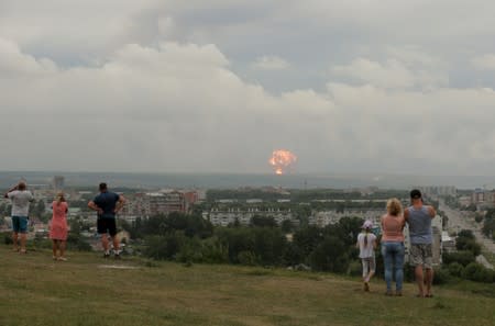 People watch flame and smoke rising from the site of blasts at an ammunition depot in Krasnoyarsk region