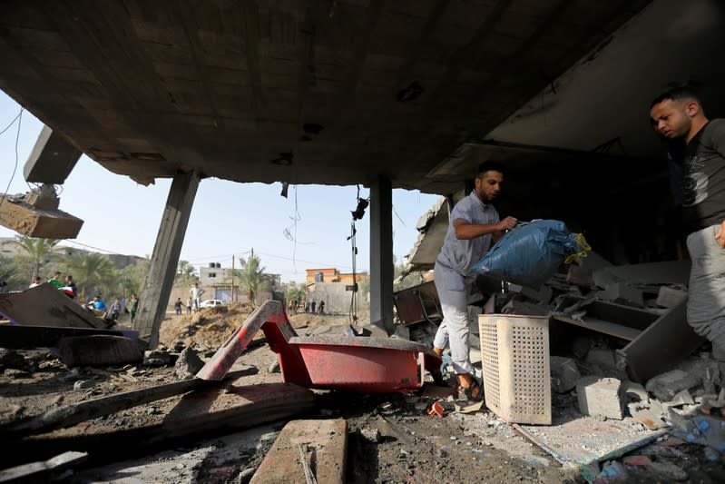 Palestinians collect belongings from a house destroyed in an Israeli air strike in the southern Gaza Strip