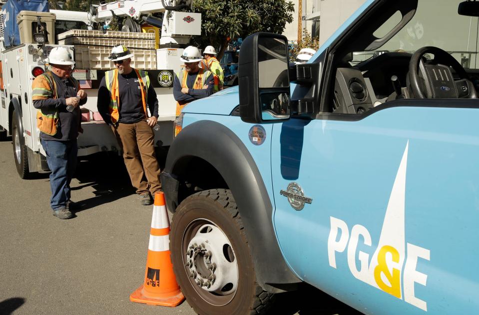 File - In this Oct. 9, 2019, file photo, Pacific Gas & Electric and Caltrans workers stand near the Caldecott Tunnel in Oakland, Calif.