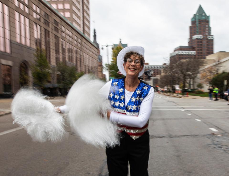 Jan Kwiatkowski, a co-leader of the Milwaukee Dancing Grannies, smiles and swings pompoms as she marches in the Veterans Day parade in Milwaukee on Saturday, Nov. 5, 2022. Kwiatkowski, 67, is a family therapist and ordained chaplain who has been a Dancing Granny since 2018. She offered to help lead the group as they have regrouped and rebuilt in the face of tragedy.