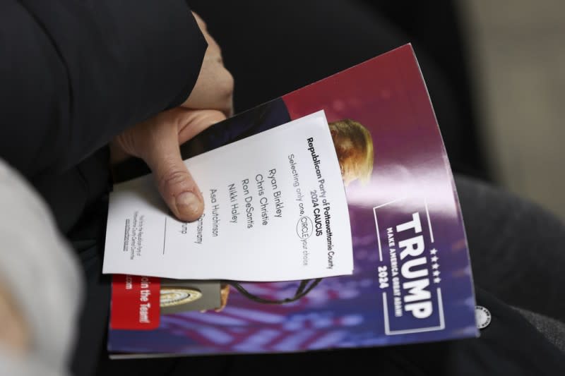<cite>2024年1月15日，美國愛荷華州一位選民拿著黨團選票和一本川普的小冊子。（美聯社）</cite>