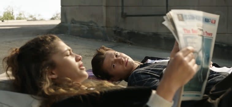 Peter lying on a rooftop with MJ, who is reading a newspaper, in "Spider-Man: No Way Home"