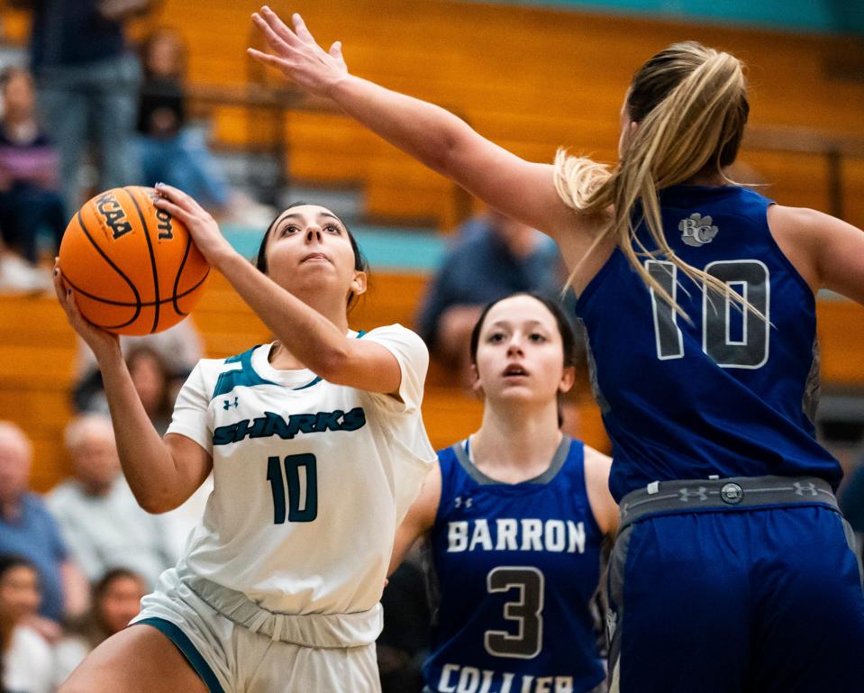 Gulf Coast Sharks guard Sophia Pasquarello (10) drives to the basket while being guarded by Barron Collier Cougars forward Regan Means (10) during the first quarter of a game at Gulf Coast High School in Naples on Tuesday, Dec. 12, 2023.