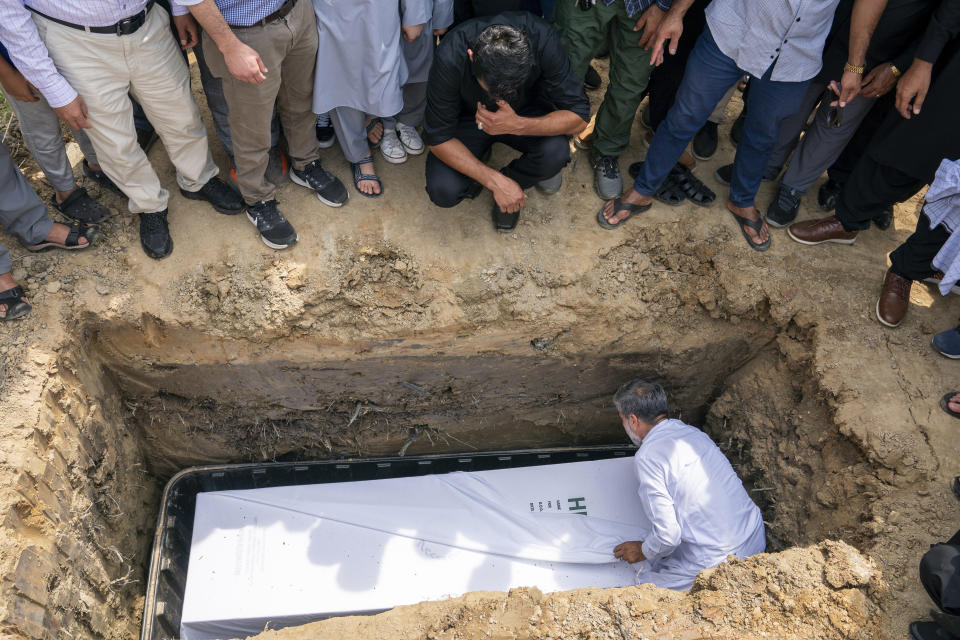 Friends and family watch as the body of Nasrat Ahmad Yar, 31, is placed into a grave during a funeral service at the All Muslim Association of America cemetery on Saturday, July 8, 2023 in Fredericksburg, Va. Ahmad Yar, an Afghan immigrant who worked as an interpreter for the U.S. military in Afghanistan, was shot and killed on Monday, July 3, while working as a ride-share driver in Washington. (AP Photo/Nathan Howard)