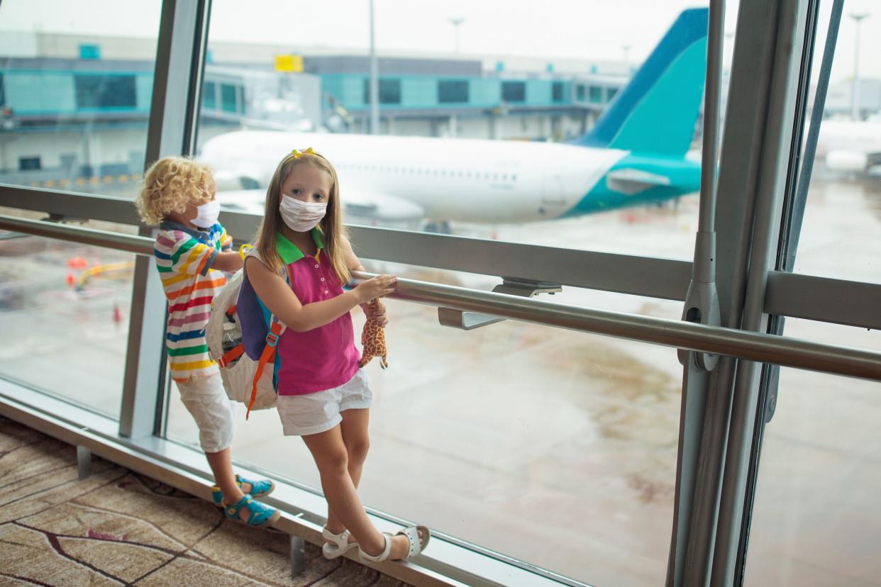 Kids at airport in face mask. Children look at airplane after coronavirus outbreak. Safe travel and flying with child in virus pandemic. Family at departure gate. Vacation after covid-19 lockdown.