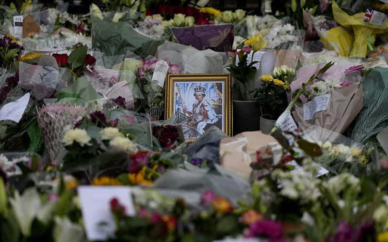 A portrait of Queen Elizabeth II sits amidst floral tributes