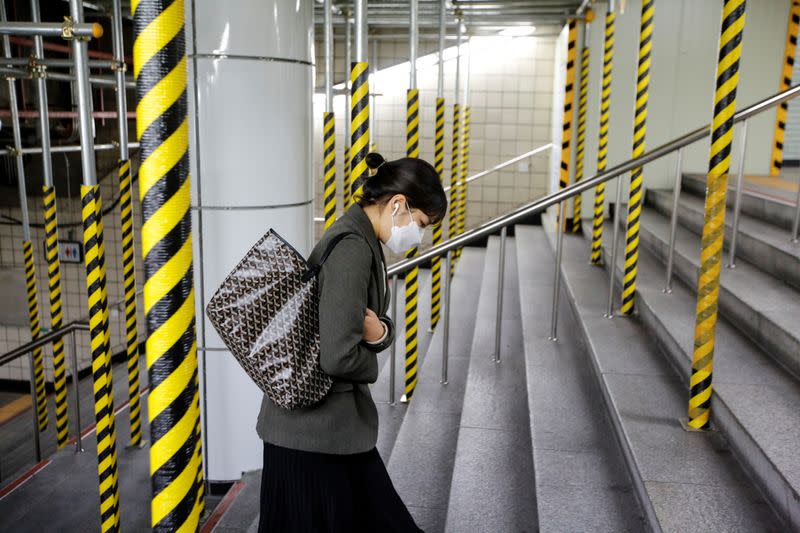 Una mujer que lleva una máscara como medida preventiva contra el coronavirus sube las escaleras de una estación de metro en Seúl, Corea del Sur