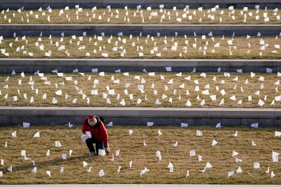 A man places flags at the National World War I Museum and Memorial last year in Kansas City. The 1,665 flags represent the Kansas City-area residents who died in the coronavirus pandemic, and the display was part of a national memorial to lives lost to COVID-19.