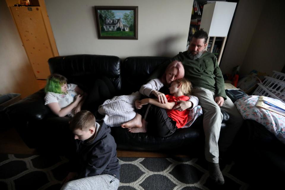 James Hogan II sits with his wife, Rebekah, daughter Caleigh, 15, and sons Sebastian, 9, and Ben, 14, in the living room of their home in Troy, N.Y. April 7, 2022. In October 2020, the entire family contracted COVID-19. Almost a year and a half later, they all suffer symptoms of long COVID. James, a disabled military veteran is on permanent disability, and has had to take on the role of caregiver for his family despite his lingering symptoms. Rebekah, a registered nurse, has been unable to work due to her COVID symptoms. As a result the family has eaten into much of their life savings. 